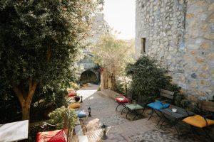 En el encantador patio de piedra del Hotel Castillo de Monda (Málaga), descubra acogedoras sillas con cojines de colores, faroles que ofrecen un brillo cálido y una exuberante vegetación que rodea el área. - ForTwo - Planes para parejas