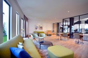 Una espaciosa sala de estar moderna que recuerda a La suite presidencial del Hotel Barceló Sevilla Renacimiento en Sevilla, con sofás verdes, mesas redondas, grandes ventanales y suelos de madera. - ForTwo - Planes para parejas