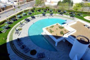 Vista aérea de la piscina circular de La suite presidencial del Hotel Barceló Sevilla Renacimiento, donde tumbonas y sombrillas toman el sol de Sevilla. - ForTwo - Planes para parejas