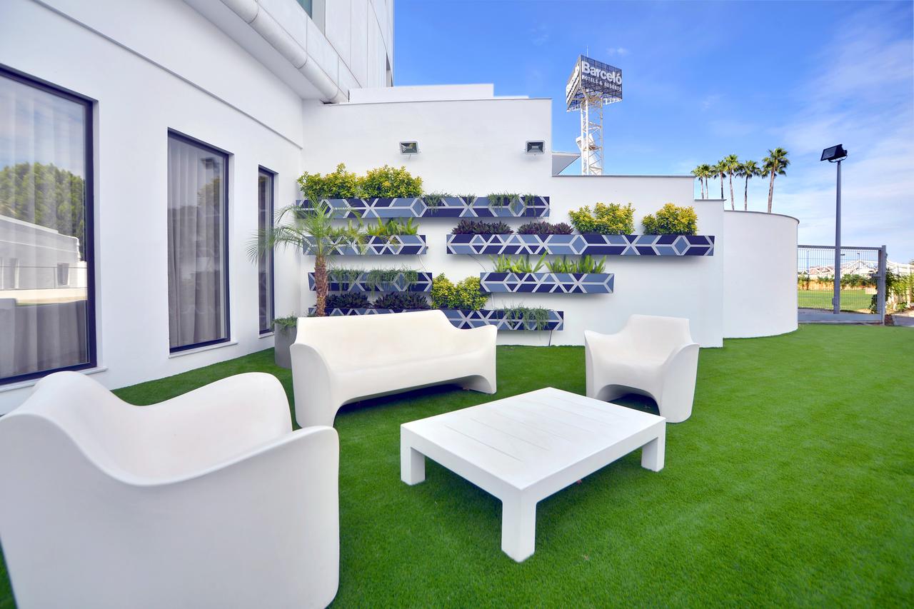 Disfrute de una moderna zona de estar al aire libre en la azotea del Hotel Barceló Sevilla Renacimiento, con muebles blancos, jardín vertical y césped artificial. Este tranquilo oasis ofrece a sus huéspedes una experiencia de lujo similar a la de La Suite Presidencial del Hotel Barceló Sevilla Renacimiento. - ForTwo - Planes para parejas