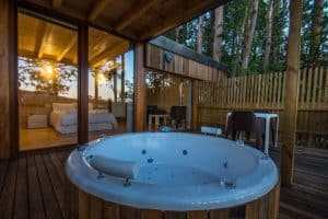 Experimente Punta Espiñeiro, el lujo de Cabanas sem Barreiras, con una bañera de hidromasaje con terraza de madera fuera de un dormitorio con paredes de vidrio, ubicado serenamente en el bosque cerca de A Coruña. - ForTwo - Planes para parejas