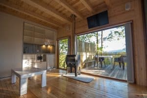 El Punta Espiñeiro el lujo de Cabanas sem Barreiras en A Coruña cuenta con un moderno interior de cabaña de madera con estufa, cocina pequeña y puertas de vidrio abiertas que dan a una terraza con vistas a la naturaleza, lo que promete un lujo sereno. - ForTwo - Planes para parejas