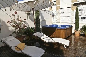 Disfrute de un romántico patio en la azotea del Alcoba del Rey de Sevilla, con dos tumbonas, una sombrilla, exuberantes plantas y un lujoso jacuzzi en una terraza de madera. - ForTwo - Planes para parejas