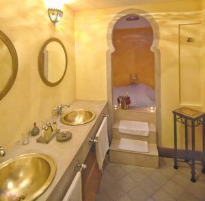 Disfrute de un baño con una cálida iluminación, lavabos y espejos dorados, que evoca las lujosas Suites románticas con jacuzzi Alcoba del Rey de Sevilla. Disfrute de un acogedor rincón de baño de burbujas, realzado por la luz de las velas y el efecto jacuzzi, con una toalla lista en el taburete. - ForTwo - Planes para parejas