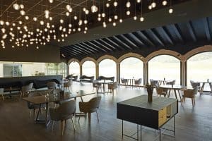 Un restaurante espacioso y moderno con grandes ventanales, iluminación elegante y mesas y sillas cuidadosamente dispuestas se encuentra cerca de la Habitación mágica en el Hotel Spa Arzuaga en Valladolid. - ForTwo - Planes para parejas