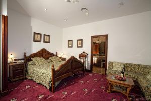 Descubre la Habitación mágica del Hotel Spa Arzuaga en Valladolid, equipada con una cama de matrimonio con motivos florales, un elegante mobiliario de madera, una mesita y una acogedora entrada al baño. - ForTwo - Planes para parejas
