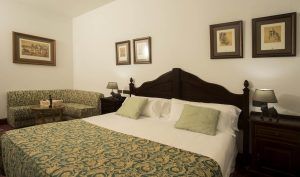 Disfruta de la Habitación mágica del Hotel Spa Arzuaga en Valladolid, que ofrece una cama de matrimonio con colcha estampada, sofá a juego y cuadros decorativos, asegurando una estancia perfecta. - ForTwo - Planes para parejas