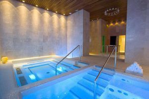 Experimente el máximo rejuvenecimiento en la Habitación mágica del Hotel Spa Arzuaga, Valladolid, equipada con lujosas comodidades de spa en el interior, como piscinas de color azul brillante, elegantes pasamanos de metal, toallas apiladas e iluminación ambiental atmosférica para una relajación serena. - ForTwo - Planes para parejas