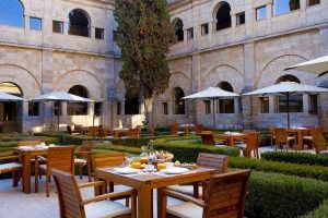 Experimente el encanto del histórico patio de piedra de Valladolid en Estancia en la Abadía Retuerta LeDomaine, con mesas de madera, sombrillas blancas y setos cuidadosamente recortados en su comedor al aire libre. - ForTwo - Planes para parejas