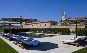 Disfrute de la piscina al aire libre con tumbonas y sombrillas en medio del encanto histórico de Estancia en la Abadía Retuerta LeDomaine (Valladolid) bajo un cielo azul claro. - ForTwo - Planes para parejas