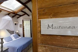 La encantadora Habitación Casa del árbol Maitenea en el Hotel Jakue (Navarra) cuenta con detalles en madera, un tragaluz y una cama con dosel, capturando la esencia de una acogedora experiencia en una casa del árbol. - ForTwo - Planes para parejas
