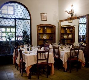 En La Posada de Pradorey en Burgos, el elegante comedor cuenta con una mesa con sillas de madera, estantes decorativos y un gran ventanal con diseño enrejado. - ForTwo - Planes para parejas
