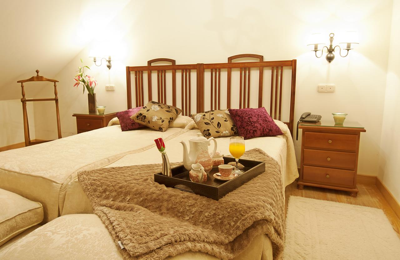 Disfrute de una acogedora estancia en La Posada de Pradorey (Burgos) en una habitación con dos camas, bandeja de aperitivos, muebles de madera y cojines decorativos y flores. - ForTwo - Planes para parejas