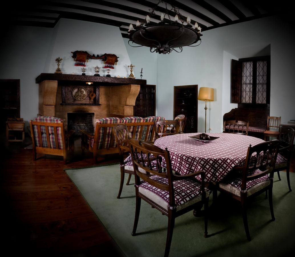 Este comedor vintage, inspirado en el encanto de La Posada de Pradorey (Burgos), luce una mesa redonda con sillas estampadas, una acogedora chimenea, una elegante lámpara de araña y una gran lámpara. - ForTwo - Planes para parejas