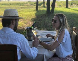 Una pareja disfruta del "Día romántico de vino y gastronomía entre viñedos (Barcelona)" en una mesa al aire libre en un campo de hierba soleado, inmerso en el encanto de los viñedos. - ForTwo - Planes para parejas