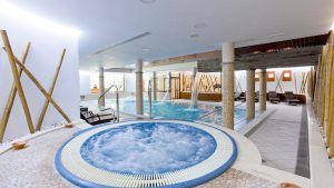 Disfrute del lujo en el spa interior del Hospes Palacio de Arenales, con jacuzzi circular y amplia piscina. Relájese en tumbonas en un entorno de madera que fusiona la elegancia natural con un diseño sofisticado. - ForTwo - Planes para parejas