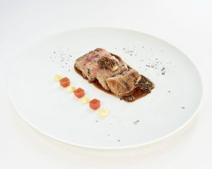 Saborea el Menú degustación del Restaurante Novodabo en Zaragoza, con tiernas lonchas de carne con sabrosa salsa, guarniciones y exquisitos chorritos sobre un impecable plato blanco. - ForTwo - Planes para parejas