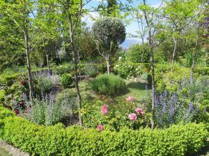 Un jardín circular con flores de colores y setos recortados se encuentra bajo un cielo azul claro, evocando el encanto de los paisajes de las Alpujarras como los cercanos a Apartamentos con cocina en las Alpujarras Cortijo Opazo (Granada). - ForTwo - Planes para parejas