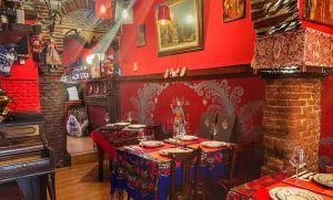 El Restaurante Noches de Moscú en Madrid ofrece un ambiente acogedor con paredes rojas, cuadros y manteles coloridos. Disfrute del "Menú ruso para dos" para una experiencia gastronómica auténtica y deliciosa. - ForTwo - Planes para parejas