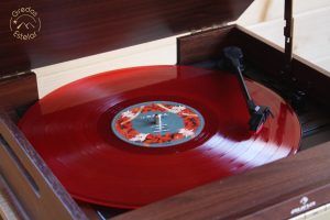 Un disco de vinilo rojo gira sobre un tocadiscos de madera vintage, cuya etiqueta floral recuerda a una escapada romántica en hotel burbuja con Gredos Estelar (Ávila). - ForTwo - Planes para parejas