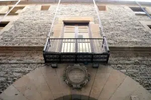 Ubicado en Barcelona, este histórico edificio de piedra con balcón cuenta con una placa que dice "Biblioteca Popular de la Dona", celebrando los logros de las mujeres ilustres. Ideal para tu recorrido cultural con el Tour Gratuito de las Mujeres Ilustres de Barcelona. - ForTwo - Planes para parejas