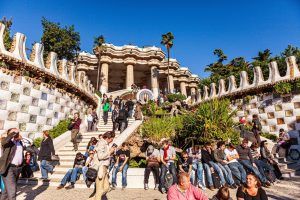 Los visitantes del Parque Güell en Barcelona disfrutan del vibrante arte bajo un cielo azul claro mientras se reúnen en bancos y escalones de mosaico durante el "Tour gratuito por el Parque Güell (Barcelona). - ForTwo - Planes para parejas
