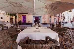 Miss Sushi Granada ofrece una encantadora experiencia gastronómica al aire libre en Granada con sillas de mimbre, manteles blancos y grandes sombrillas en una hermosa calle adoquinada. - ForTwo - Planes para parejas