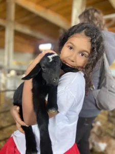 En Cal Serrats, Barcelona, un niño vestido con una camisa blanca sostiene tiernamente un cabrito negro durante "Una mañana haciendo de pastor". - ForTwo - Planes para parejas