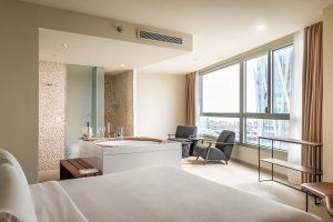 Disfrute de una moderna habitación de hotel en el Hotel con jacuzzi SB Diagonal Zero en Barcelona, que cuenta con una cama grande, un acogedor jacuzzi junto a la ventana, dos sillones e impresionantes vistas a la ciudad. - ForTwo - Planes para parejas