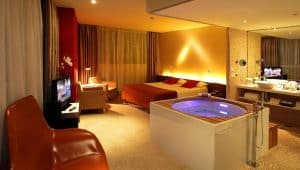 Disfrute de un retiro elegante en el Hotel con jacuzzi SB Diagonal Zero en Barcelona, que cuenta con una habitación moderna con una lujosa cama doble, TV, iluminación acogedora y un atractivo jacuzzi cerca de la elegante sala de estar. - ForTwo - Planes para parejas