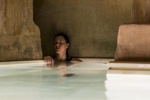 En una piscina spa cubierta con poca luz y paredes de piedra, alguien disfruta de la tranquilidad del "Pack noche + spa en el paraíso más exclusivo de agua termal milenaria (Barcelona). - ForTwo - Planes para parejas