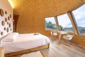 Disfruta de una acogedora habitación con cama redonda, paredes de madera y grandes ventanales para disfrutar de una vista panorámica como la del Iglús panorámicos en plena Selva de Irati (Navarra), con una pequeña mesa y sillas para admirar la belleza del paisaje. - ForTwo - Planes para parejas