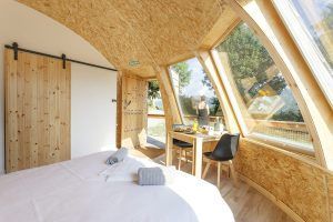 El interior de esta cabaña de madera ofrece un acogedor conjunto de cama y mesa, complementado por grandes ventanales que proporcionan vistas panorámicas que recuerdan a los Iglús panorámicos en plena Selva de Irati, Navarra. - ForTwo - Planes para parejas