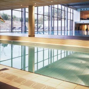El área de la piscina cubierta cuenta con grandes ventanales, una terraza de madera y vista a los árboles, lo que la hace perfecta para disfrutar del Almuerzo, Circuito de Spa y habitación romántica con Cava y Fresas (Barcelona) después de nadar. - ForTwo - Planes para parejas