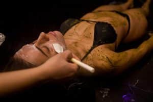 Durante una tranquila Experiencia Hammam Vital en Madrid, similar a un baño turco, las personas se relajan con un tratamiento facial refrescante mientras visten bikinis y están cubiertas con una pasta de hierbas verdes, capturando la serenidad ideal para parejas que buscan relajación. - ForTwo - Planes para parejas
