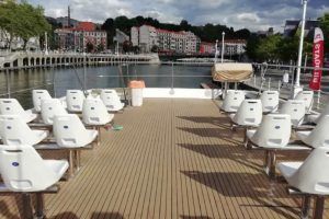 Experimente la tranquilidad en un paseo en barco por Bilbao con asientos vacíos frente al impresionante paisaje urbano bajo un cielo nublado. - ForTwo - Planes para parejas