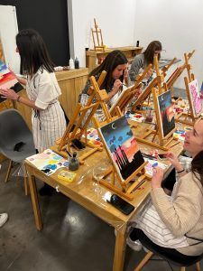 En una vibrante clase de Wine Gogh - Pintar mientras bebes vino (Barcelona), los participantes pintan coloridas escenas de atardeceres en lienzos en sus caballetes, capturando la belleza efímera con cada pincelada. - ForTwo - Planes para parejas