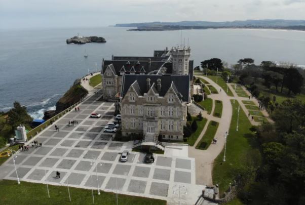 Desde una vista aérea, la Visita al Palacio de la Magdalena (Santander) revela su majestuosidad junto al mar, rodeada de frondosos senderos y vegetación. Esta joya histórica es una visita obligada en la encantadora ciudad costera. - ForTwo - Planes para parejas