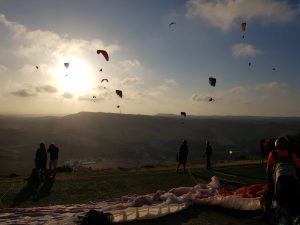 El Vuelo en parapente biplaza en Vejer (Cádiz) ofrece vuelos en parapente contra el cielo del atardecer de Cádiz, con los entusiastas preparándose en una colina cubierta de hierba cerca de Vejer. - ForTwo - Planes para parejas