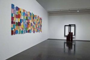 La galería de arte, que se hace eco del espíritu vibrante de Barcelona, muestra la Entrada al Museo de Arte Contemporáneo con arte abstracto rectangular colorido a la izquierda y una escultura geométrica oscura a la derecha, invitándote a un espacio cultural moderno. - ForTwo - Planes para parejas