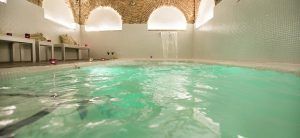 Experimente el sereno Spa Bodyna en Hospes Puerta de Alcalá, que cuenta con una piscina cubierta con un techo de ladrillo arqueado, una iluminación suave y una cascada relajante, ideal para relajarse después de un romántico "Spa y cena para dos". - ForTwo - Planes para parejas