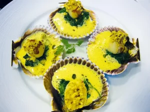 En el restaurante Nectari, disfrute de vieiras en concha con salsa amarilla y verduras. Este menú degustación con estrella Michelin ofrece un exquisito sabor a mar, llevando una delicia culinaria a su mesa. - ForTwo - Planes para parejas