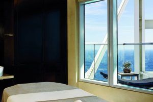 Disfrute del Desayuno, Spa de Lujo y Masaje: La Experiencia Total en el Hotel Arts, que cuenta con una relajante sala de spa con mesa de masajes, una gran ventana con vista al mar y una planta en maceta: un escape perfecto. - ForTwo - Planes para parejas
