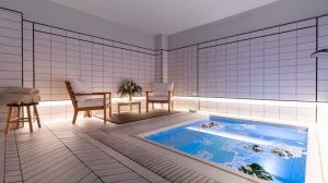 Relájese en el tranquilo spa interior del Gran Hotel Inglés de Madrid, con una relajante piscina azul y paredes de azulejos blancos. Disfrute de la experiencia "Jacuzzi y Masaje en Privado", con relajantes sesiones de jacuzzi, sillas de madera e iluminación suave para una escapada de bienestar inigualable. - ForTwo - Planes para parejas