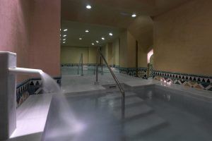 Experimente el Sumérgete en un circuito Acuático para Parejas de 60 minutos en Macià Real De La Alhambra en Granada, donde la iluminación tenue, los grifos de agua corriente, las paredes de azulejos y los elegantes pasamanos de metal crean un ambiente sereno para su aventura en la piscina cubierta del spa. - ForTwo - Planes para parejas