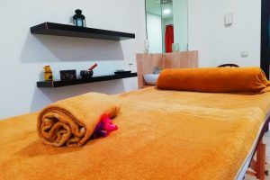 En una acogedora sala adornada con una decoración que ofrece relajación, una camilla de masaje con toallas de color naranja refleja una tranquilidad propia de Playa Granada Club Resort & Spa, famoso por su "Ritual de relajación acuática con masaje de esencias y copa de cava en pareja". - ForTwo - Planes para parejas