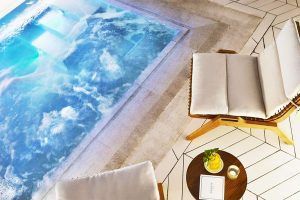 Relájese junto a la piscina del Gran Hotel Inglés con dos sillas acolchadas y una pequeña mesa redonda para tomar una copa y leer un libro. Disfrute de la tranquilidad antes de disfrutar de una experiencia rejuvenecedora con jacuzzi y masaje privado en Madrid. - ForTwo - Planes para parejas