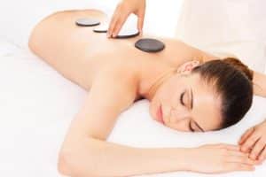 Relajándose sobre una toalla blanca en el Granada Palace & Spa, la persona disfruta de un "Circuito termal y masaje con piedras calientes en el Granada Palace & Spa (Granada)" con los ojos suavemente cerrados. - ForTwo - Planes para parejas