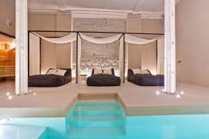 Disfrute del Masaje vegano con aromaterapia y acceda al Yurbban Passage Hotel & Spa en Barcelona. Este lujoso spa ofrece dos camas con dosel, una piscina luminosa con escalones e iluminación tenue en paredes de ladrillo blanco para una relajación total. - ForTwo - Planes para parejas