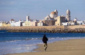 Mientras alguien pasea por la playa de arena, el horizonte histórico de Cádiz, con sus icónicos edificios con cúpulas, proporciona un impresionante telón de fondo en esta "Visita guiada por la historia de Cádiz". - ForTwo - Planes para parejas